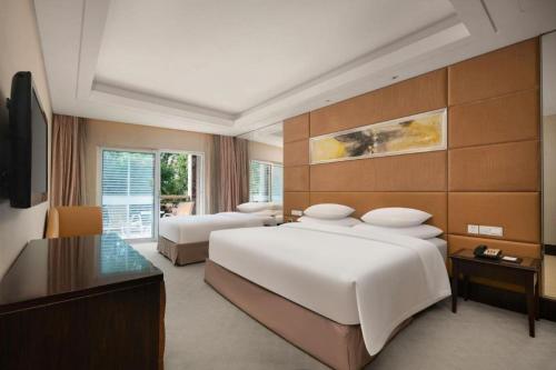 a hotel room with two beds and a television at New Century Grand Hotel Xuzhou in Xuzhou