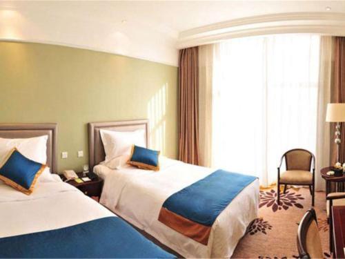 a hotel room with two beds and a chair at Datong Hotel in Datong