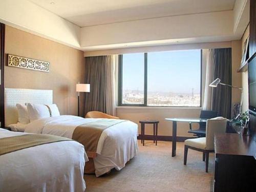 a hotel room with two beds and a desk and a window at Datong Hotel in Datong