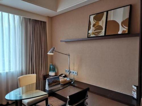 a room with a desk and a table with a lamp at Datong Hotel in Datong
