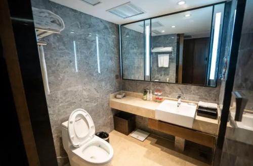 a bathroom with a toilet and a sink and a mirror at Linyi Blue Horizon Intenational Hotel in Linyi