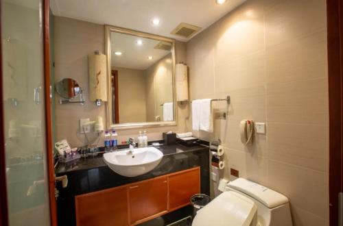 a bathroom with a sink and a toilet and a mirror at Linyi Blue Horizon Intenational Hotel in Linyi