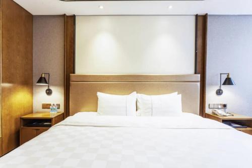 a bedroom with a large bed with white sheets and pillows at Linyi Blue Horizon Intenational Hotel in Linyi
