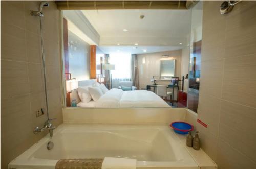 a bathroom with a bath tub with a bed in the mirror at Linyi Blue Horizon Intenational Hotel in Linyi