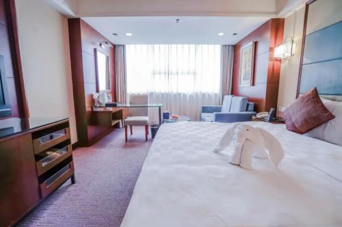 a hotel room with a large bed with a towel on it at Linyi Blue Horizon Intenational Hotel in Linyi