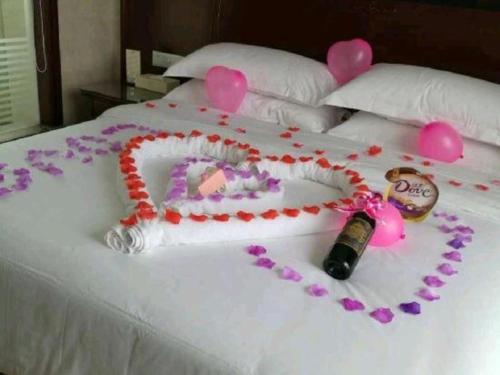 a white bed with a bottle of wine and pink hearts at Vienna Hotel Guiyang Jiaxiulou Jichang Road in Guiyang