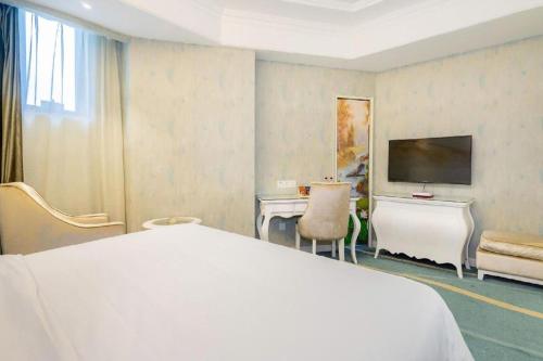 a bedroom with a bed and a desk and a television at Vienna Hotel Guiyang Jiaxiulou Jichang Road in Guiyang