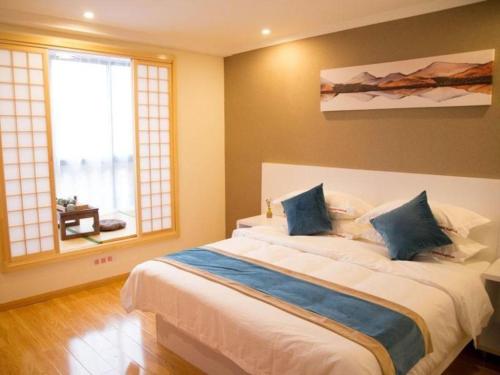 a bedroom with a large white bed with blue pillows at Shell Shanghai Songjiang District Xinqiao Town Xinqiao Hotel in Chunshen
