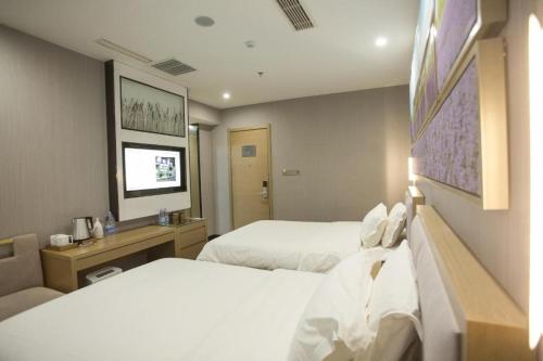 a hotel room with two beds and a desk at Lavande Hotels Heze Changjiang Road Wanda Plaza in Zhaolou