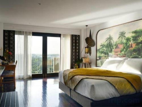 a bedroom with a large bed and a large window at RXV Wellness Village in Nakhon Pathom
