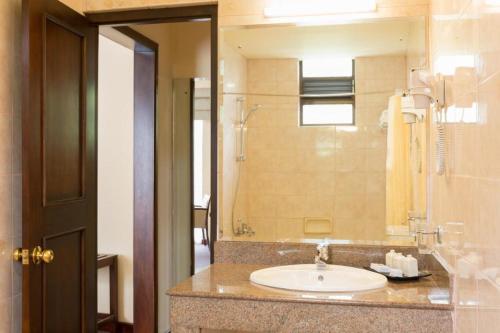 a bathroom with a sink and a large mirror at Devon Hotel in Kandy