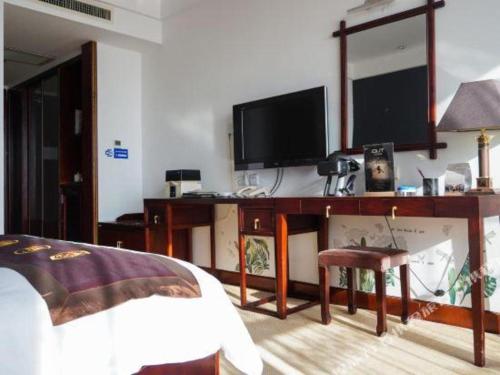 a bedroom with a desk with a tv and a bed at Datong Tiangui International Hotel in Datong