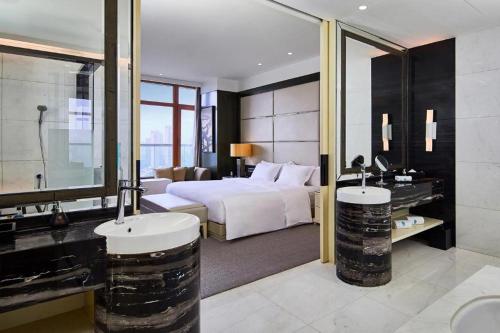 a hotel room with a bed and two sinks at Banyan Tree Tianjin Riverside in Tianjin