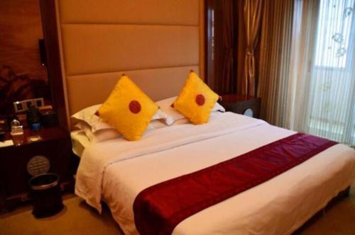 a bedroom with a large bed with two yellow pillows at Datong Tiangui International Hotel in Datong