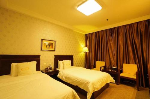 a hotel room with two beds and a chair at Datong Tiangui International Hotel in Datong