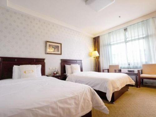 a hotel room with two beds and a chair at Datong Tiangui International Hotel in Datong
