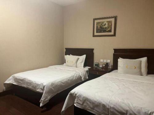 a bedroom with two beds with white sheets at Datong Tiangui International Hotel in Datong