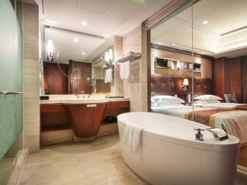 a bathroom with a bath tub and a bed at Maison New Century Hotel Wuyuan Haiyan in Jiaxing
