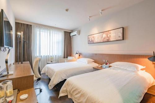 a hotel room with two beds and a desk at Jinjiang Inn Hangzhou Xihu Avenue Branch in Hangzhou
