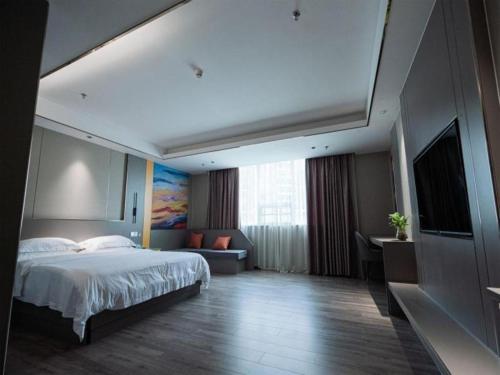 a hotel room with a bed and a television at GreenTree Inn Meizhou Meijiang District Wanda Plaza Hotel in Meizhou