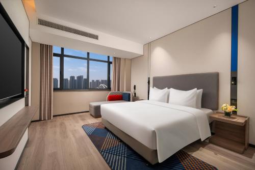 a hotel room with a large bed and a large window at Holiday Inn Express Qingdao City Balcony by IHG in Qingdao
