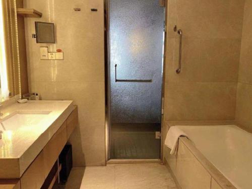a bathroom with a shower and a sink and a tub at Dusit D2 Binhu Changzhou Hotel in Changzhou