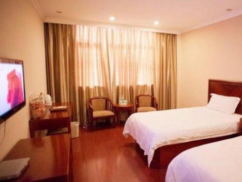 a hotel room with a bed and a television at GreenTree Inn Heze Mudan Road Bus Terminal Station Express Hotel in Heze