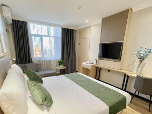 a hotel room with a bed and a television at GreenTree Inn Xinjiang Uygur Autonomous Region Korla Bazhou Bus Terminal Beishan Road Express Hotel in Korla