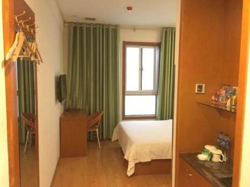 a bedroom with a bed and a window with green curtains at GreenTree Inn Hefei Huangshan Road Daxidi 1912 Express Hotel in Hefei