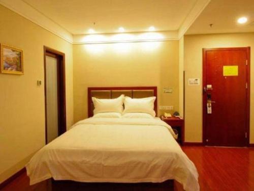 a bedroom with a large bed with white sheets at GreenTree Inn Hefei Huangshan Road Daxidi 1912 Express Hotel in Hefei