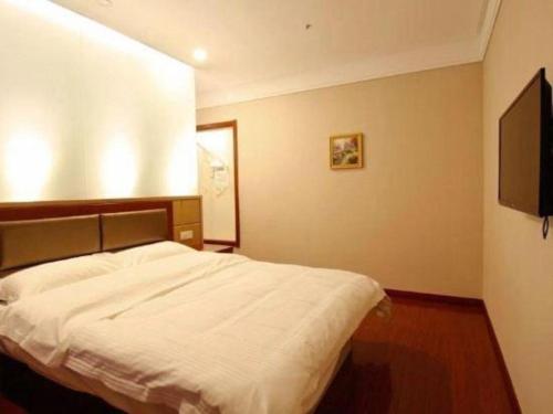 a bedroom with a bed and a flat screen tv at GreenTree Inn Hefei Huangshan Road Daxidi 1912 Express Hotel in Hefei