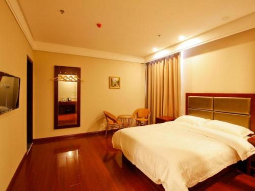 a bedroom with a white bed and a table and chairs at GreenTree Inn Hefei Huangshan Road Daxidi 1912 Express Hotel in Hefei
