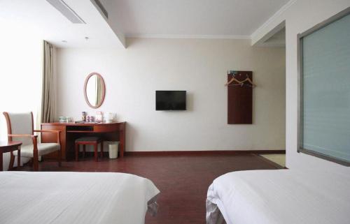 a room with two beds and a desk with a mirror at GreenTree Inn Yancheng Vehicle Administrative office Test Center Express Hotel in Yancheng