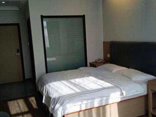 a bedroom with a white bed with a large window at GreenTree Inn Yancheng Vehicle Administrative office Test Center Express Hotel in Yancheng