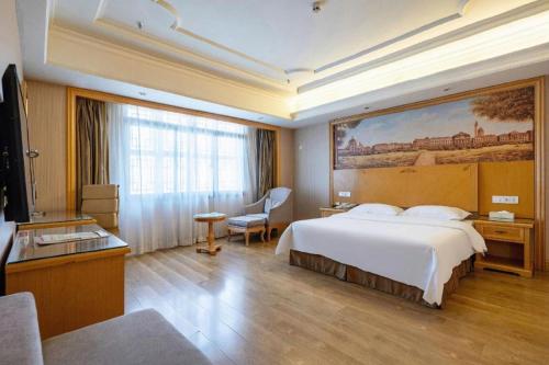 une chambre d'hôtel avec un lit et un grand tableau sur le mur dans l'établissement Vienna International Hotel Lhasa Potala Palace, à Lhasa