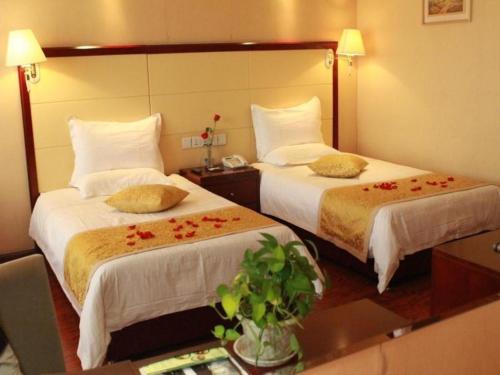 two beds in a hotel room with flowers on them at GreenTree Inn Taiyuan PinGYAng Road Business Hotel in Taiyuan