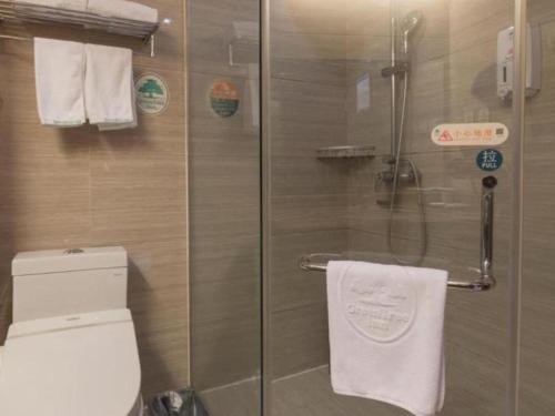 a bathroom with a shower with a toilet and towels at GreenTree Inn Taiyuan PinGYAng Road Business Hotel in Taiyuan