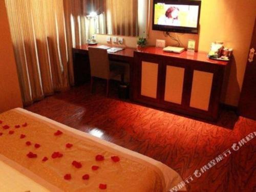a hotel room with a desk and a bed with roses on it at GreenTree Inn Taiyuan PinGYAng Road Business Hotel in Taiyuan