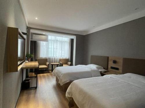 a hotel room with two beds and a television at GreenTree Inn Hefei Chenghuangmiao San Xiao Kou Subway Station Hotel in Hefei