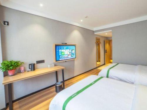 a bedroom with two beds and a tv on the wall at GreenTree Inn Hefei Chenghuangmiao San Xiao Kou Subway Station Hotel in Hefei