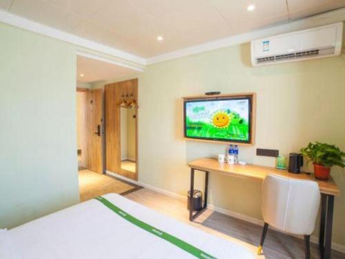 a bedroom with a desk and a tv on the wall at GreenTree Inn Hefei Chenghuangmiao San Xiao Kou Subway Station Hotel in Hefei