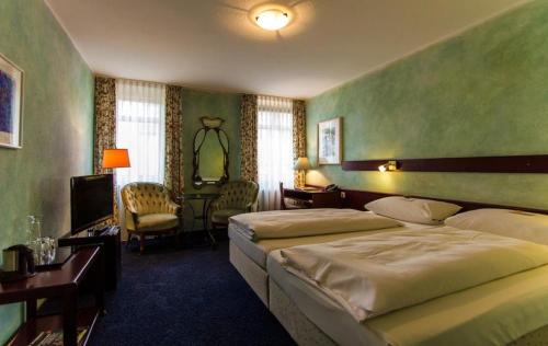 1 Schlafzimmer mit 2 Betten, einem Schreibtisch und einem TV in der Unterkunft STADT-Hotel Lörrach GbR in Lörrach