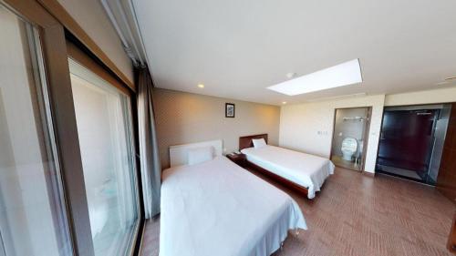 a hotel room with two beds and a window at Sea View Hotel in Jeju