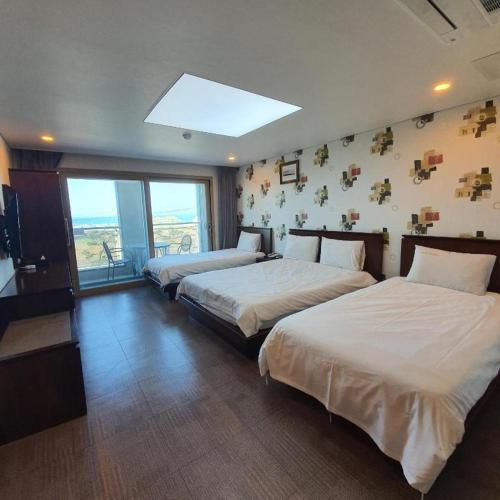 a bedroom with two beds and a large window at Sea View Hotel in Jeju