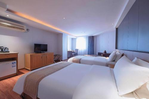 a hotel room with two beds and a television at Zhongshan Louis Hotel in Zhongshan