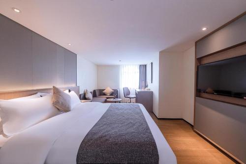 a hotel room with a large bed and a flat screen tv at Zhongshan Louis Hotel in Zhongshan