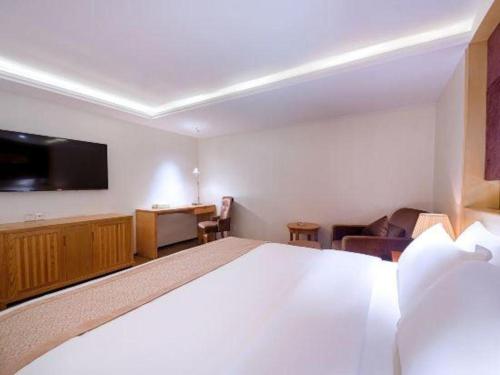 a hotel room with a large bed and a flat screen tv at Zhongshan Louis Hotel in Zhongshan