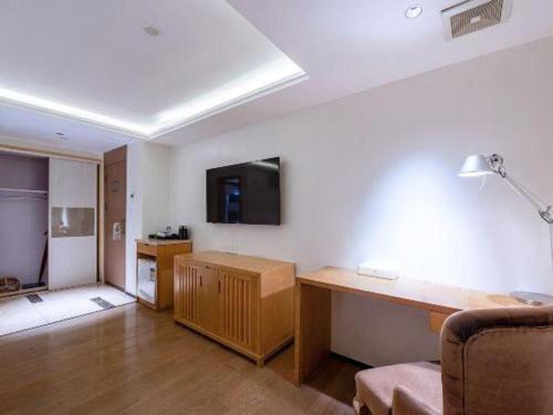 a living room with a desk and a tv on the wall at Zhongshan Louis Hotel in Zhongshan