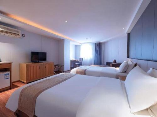 a hotel room with two beds and a television at Zhongshan Louis Hotel in Zhongshan