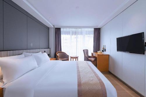 a hotel room with a large bed and a television at Zhongshan Louis Hotel in Zhongshan